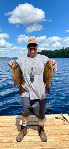 Guest Standing on Dock Displaying Two Bass he Caught