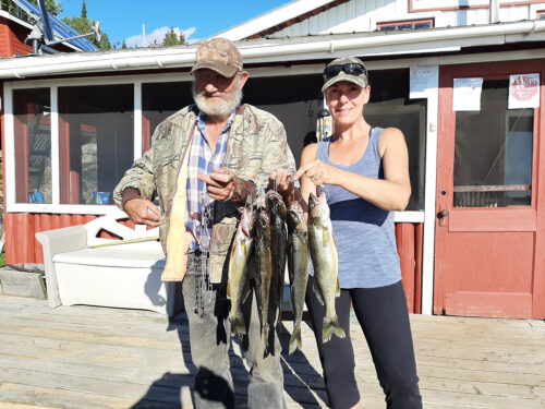 man and woman holding up stringer of fish outside the lodge