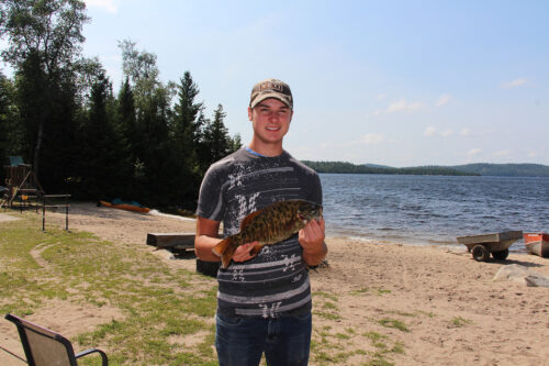 Teen Holding Bass Catch on Shore